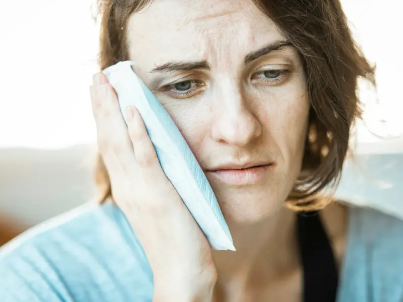 Woman holding a cold compress to her cheek for a toothache