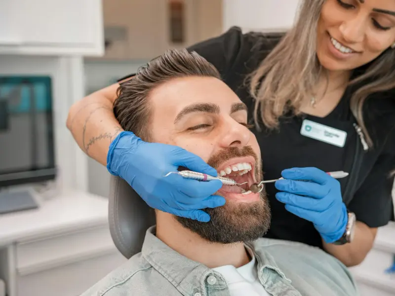 Hygienist examining a smiling patient's teeth during a routine checkup