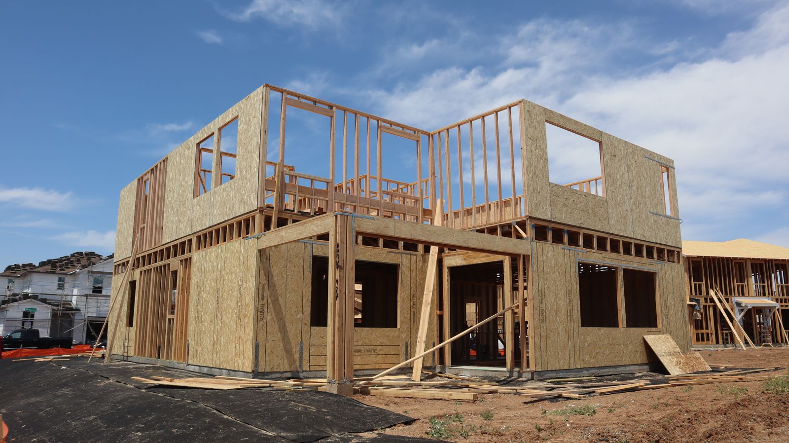 Wood framing of a two-story home addition under a blue sky