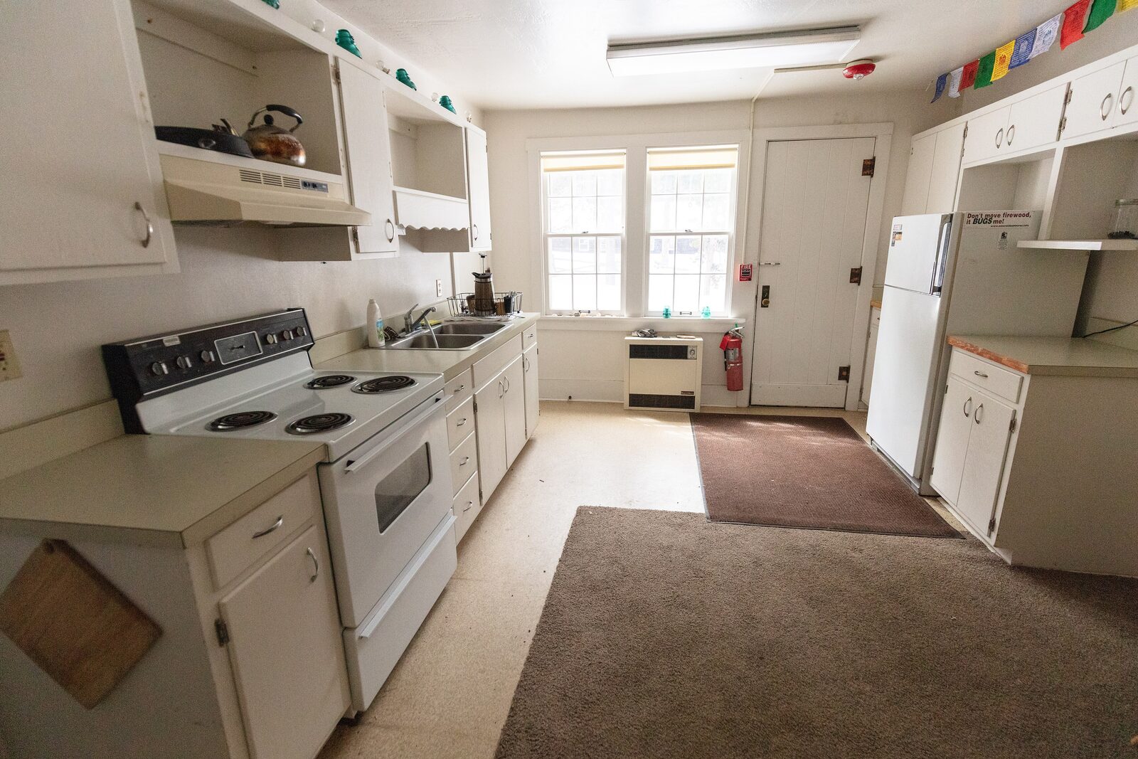 The original kitchen with open shelving, old appliances, and carpet runners