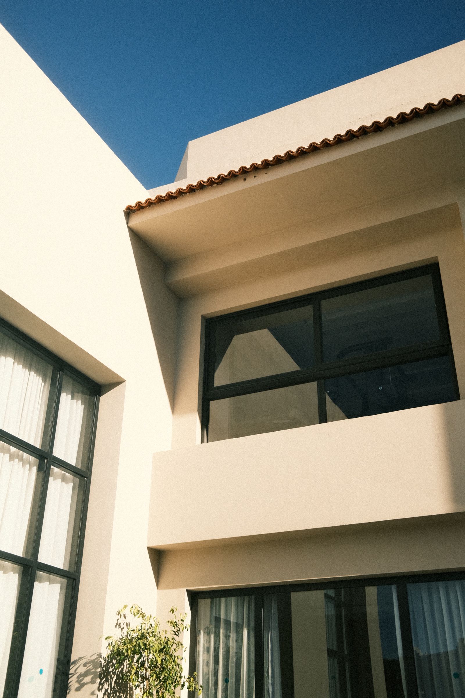 Finished modern custom home with large windows under a clear sky