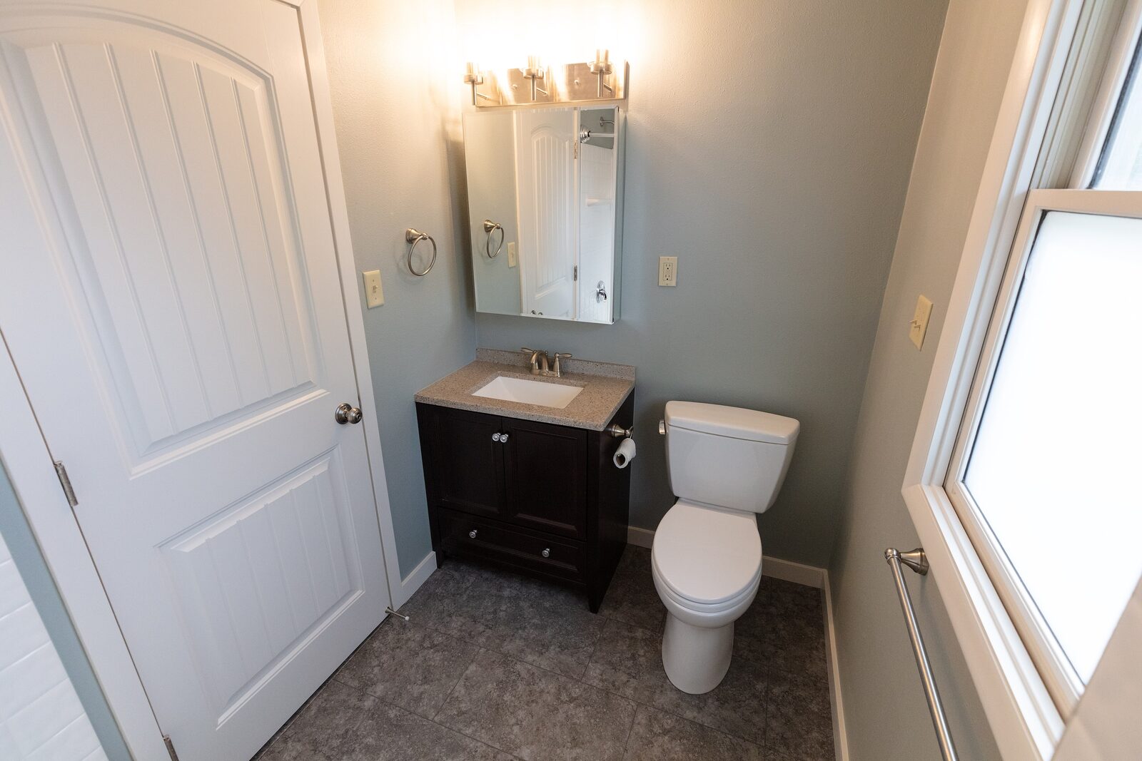 The updated hall bath with a new vanity, lighting, and door