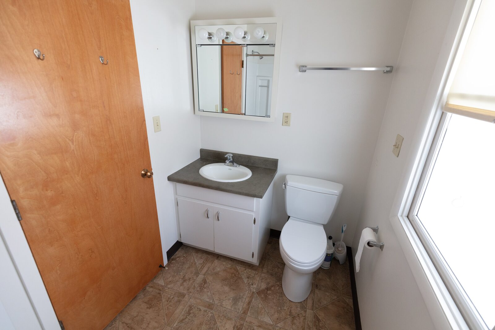 The original hall bath with a dated vanity and medicine cabinet