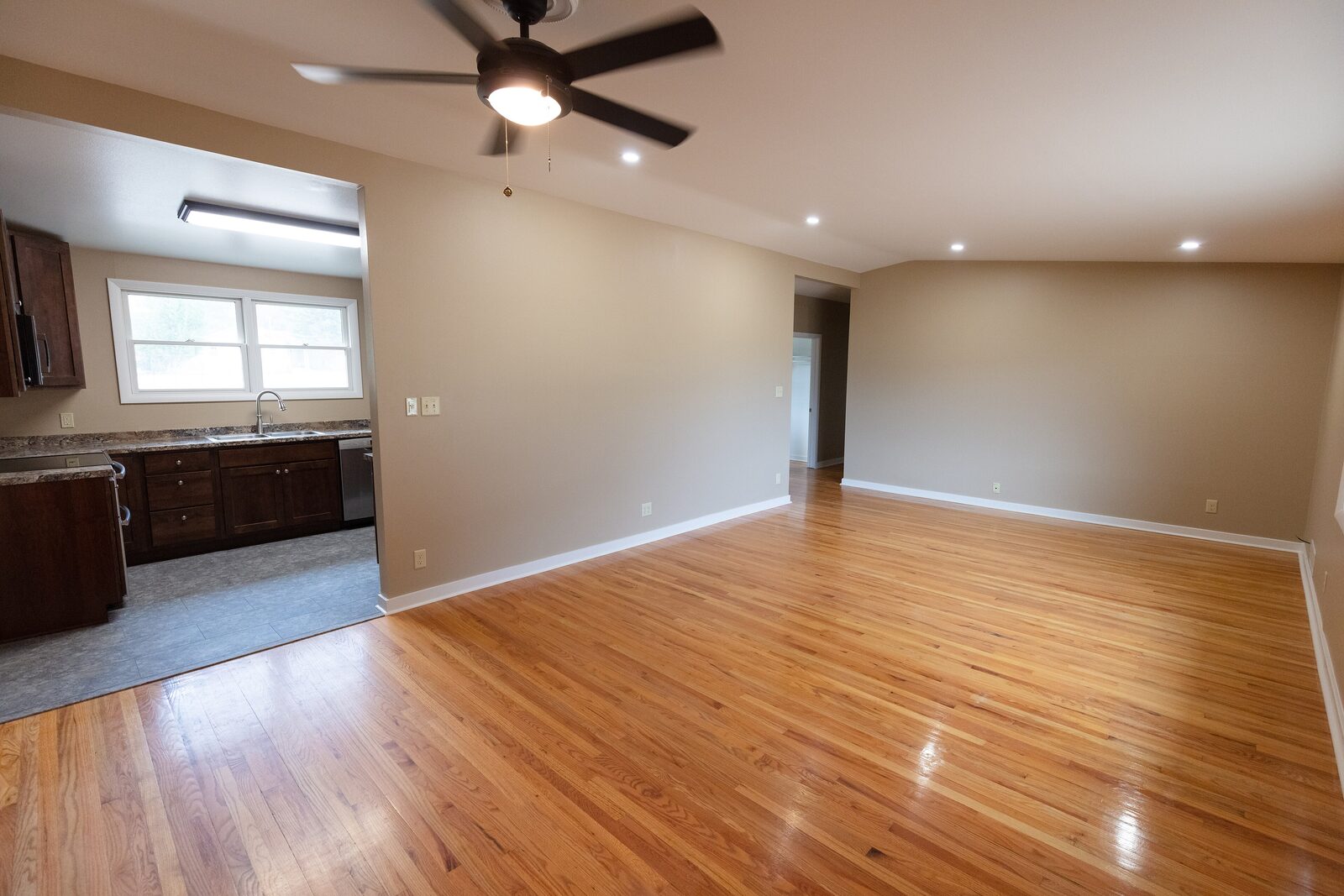 Living room with refinished oak floors, recessed lights, and a ceiling fan