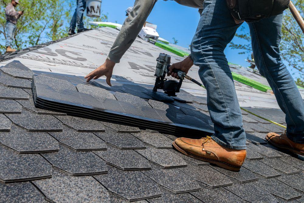 Roofer nailing new shingles over synthetic underlayment