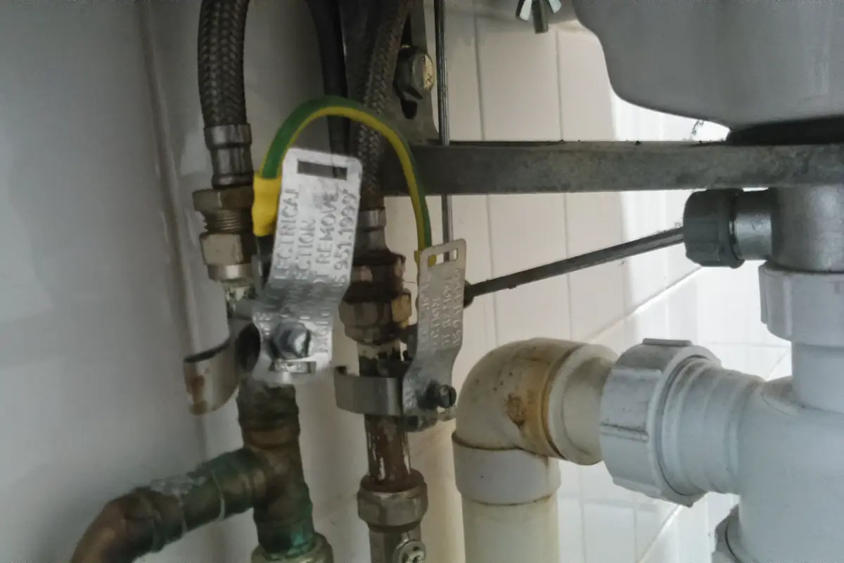 Plumbing under a bathroom sink with a white PVC drain trap and chrome shutoff valves